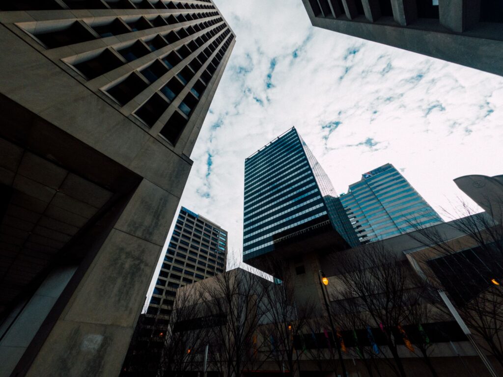 From below of aged and contemporary multistage building exteriors under cloudy sky in city
